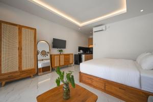 a bedroom with a bed and a table and a tv at De Luxora Villa Canggu in Kerobokan