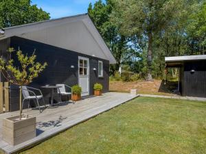 ein schwarzes Haus mit einer Holzterrasse und einem Garten in der Unterkunft Holiday Home Marise - from the sea by Interhome in Hals