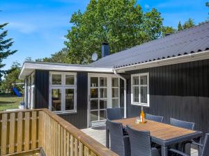 ein winziges Haus mit einem Tisch und Stühlen auf einer Terrasse in der Unterkunft Holiday Home Marise - from the sea by Interhome in Hals