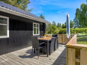 eine Terrasse mit Tisch und Stühlen auf einem Deck in der Unterkunft Holiday Home Marise - from the sea by Interhome in Hals