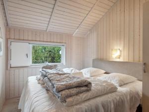 a bedroom with a bed with white sheets and a window at Holiday Home Hane - 150m from the sea by Interhome in Hadsund