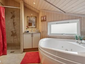 a bathroom with a tub and a shower with a window at Holiday Home Hane - 150m from the sea by Interhome in Hadsund