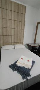 una cama con dos toallas blancas y una mesa en Hotel Chalé Centro, en Curvelo