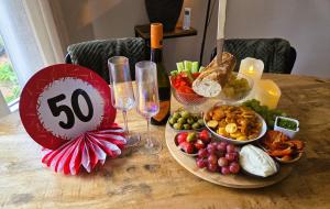 a table with a plate of food and wine glasses at "Huisje op de Veluwe" met privé Jacuzzi en Bar! in Ermelo
