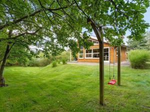 a house with a tree with a swing in the yard at Holiday Home Krister - 250m to the inlet by Interhome in Farsø