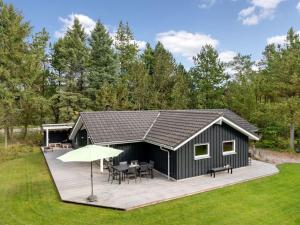 a black shed with a deck and a table and umbrella at Holiday Home Grimi - 4km from the sea by Interhome in Fjerritslev