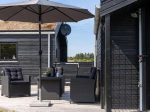 un patio con dos sillas y una sombrilla en Holiday Home Dyke - 1-5km from the sea by Interhome, en Saltum