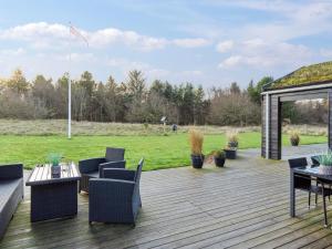 Una terraza de madera con muebles y un cenador. en Holiday Home Dyke - 1-5km from the sea by Interhome, en Saltum