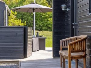 Un porche de madera con una sombrilla y un banco. en Holiday Home Dyke - 1-5km from the sea by Interhome, en Saltum