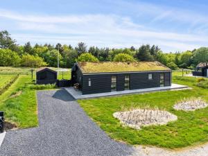 Una pequeña cabaña negra con techo de hierba. en Holiday Home Dyke - 1-5km from the sea by Interhome, en Saltum
