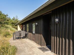 a black building with a table and chairs on a patio at Holiday Home Marite - 200m from the sea by Interhome in Pandrup