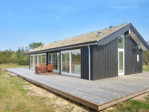 a black house with a deck with chairs on it at Holiday Home Melinda - 2km from the sea by Interhome in Pandrup