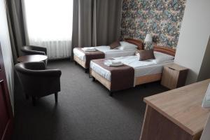 a hotel room with two beds and a chair at Noclegi-Restauracja Boss in Mogilno