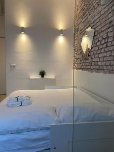 ミラノにあるDream - a nest in Porta Veneziaの白いベッドとレンガの壁が備わるベッドルーム1室が備わります。 +6枚の写真
