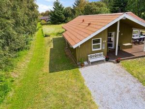 a small green house with a bench in front of it at Holiday Home Karitte - 5km from the sea by Interhome in Fjerritslev