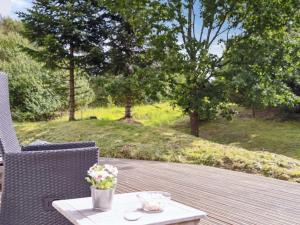 a wooden deck with two chairs and a table with flowers at Holiday Home Karitte - 5km from the sea by Interhome in Fjerritslev