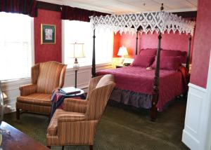 um quarto com uma cama de dossel e uma cadeira em Stafford's Bay View Inn em Petoskey