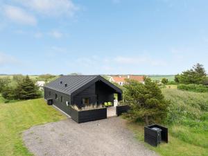 a black house with a black roof on a field at Holiday Home Odinkar - 1-1km from the sea by Interhome in Hjørring