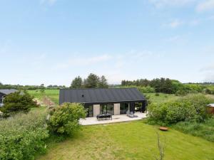 a house with a black roof in a field at Holiday Home Odinkar - 1-1km from the sea by Interhome in Hjørring