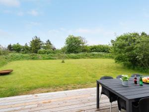 a table and chairs on a deck with a large field at Holiday Home Odinkar - 1-1km from the sea by Interhome in Hjørring