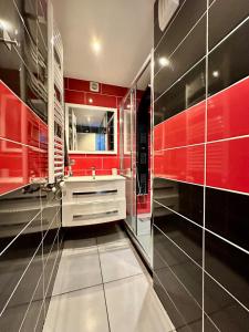 a red bathroom with a sink and a mirror at Grand et Bel appartement 6 personnes in Valence