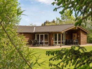 a log cabin with a table and chairs in a yard at Holiday Home Els - 900m from the sea by Interhome in Fjerritslev