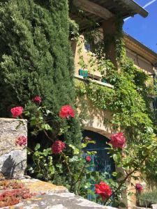 un bâtiment avec des roses rouges devant une fenêtre dans l'établissement La Maison près de la Fontaine, à Salles-sous-Bois