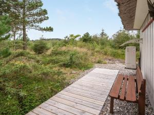 a wooden walkway with a bench next to a building at Holiday Home Waldar - 900m from the sea by Interhome in Fjerritslev +25 photos