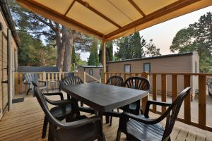 een terras met een tafel en stoelen op een dek bij Vertacoflav in Carry-le-Rouet