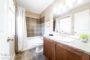 a bathroom with a sink and a toilet and a tub at Chic 6BDRM Getaway - KingBed - Patio - BBQ - Garage - Wifi in Edmonton +91 photos