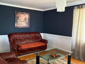 a living room with a leather couch and a glass table at Casa Larisa Borsa in Borsa