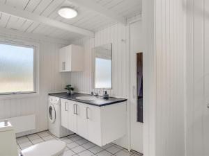 a white bathroom with a sink and a washing machine at Holiday Home Franka - 950m from the sea by Interhome in Hjørring +13 photos