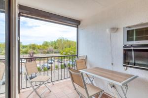 eine Küche mit einem Tisch und Stühlen sowie einen Balkon in der Unterkunft Le Grau-du-roi in Le Grau-du-Roi