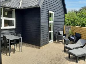 un patio con mesa y sillas junto a un edificio en Holiday Home Alfuin - 500m from the sea by Interhome, en Hjørring