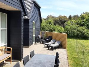 Un patio con sillas y mesas y una valla. en Holiday Home Alfuin - 500m from the sea by Interhome, en Hjørring