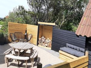 un patio con mesa, sillas y banco en Holiday Home Alfuin - 500m from the sea by Interhome, en Hjørring