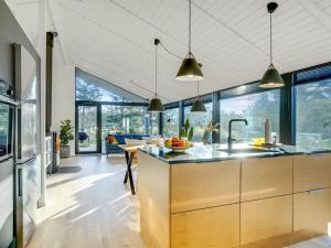 a kitchen with wooden cabinets and glass windows at Holiday Home Remko - 1-5km from the sea by Interhome in Hjørring +15 photos