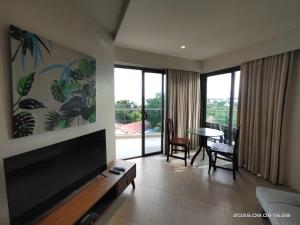 a living room with a flat screen tv and a table at Rent Homecation at Tambuli Seaside Living in Maribago
