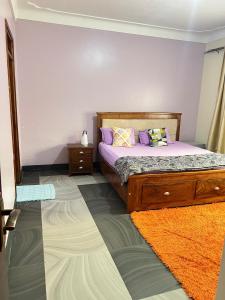 a bedroom with a bed with purple sheets and pillows at Rubys haven in Jinja