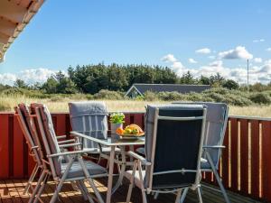 three chairs and a table with a bowl of fruit on a patio at Holiday Home Bertie - 700m from the sea by Interhome in Hirtshals +17 photos