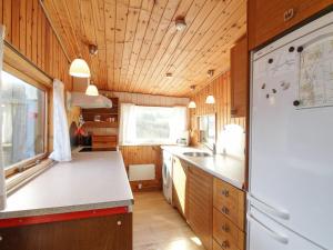a kitchen with a white refrigerator and wooden walls at Holiday Home Nea - 234m from the sea by Interhome in Hirtshals