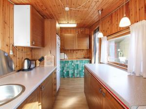 a kitchen with wooden cabinets and a counter top at Holiday Home Nea - 234m from the sea by Interhome in Hirtshals +8 photos