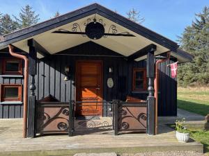 a black cottage with a porch and a door at Holiday Home Marla - 1-1km from the sea by Interhome in Bindslev