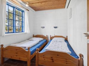 two beds in a room with two windows at Holiday Home Ema - 5km from the sea by Interhome in Læsø +12 photos