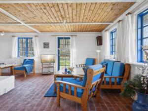 a living room with blue chairs and a wooden ceiling at Holiday Home Ema - 5km from the sea by Interhome in Læsø