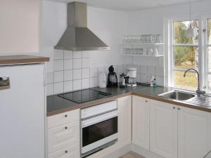 a white kitchen with a sink and a stove top oven at Holiday Home Siggi - 400m from the sea by Interhome in Jerup