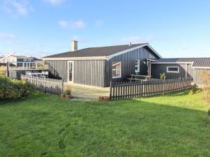 a house with a fence in front of a yard at Holiday Home Vili - 441m from the sea by Interhome in Hirtshals