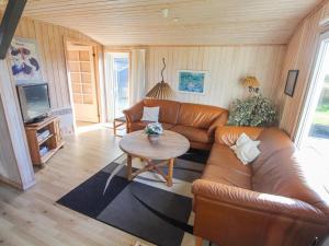 a living room with a leather couch and a table at Holiday Home Vili - 441m from the sea by Interhome in Hirtshals +14 photos