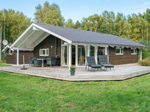 a log cabin with a deck and chairs on it at Holiday Home Thomasine - 1-5km from the sea by Interhome in Læsø