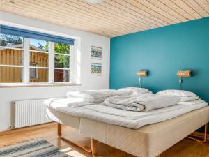 a bed in a room with a blue wall at Holiday Home Tara - 300m from the sea by Interhome in Læsø